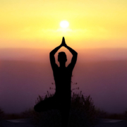 Well-being1 a silhouette of a woman in a yoga pose on a click edge with the sun setting in the distance